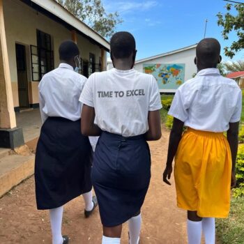Three girls walking together outside of a school.